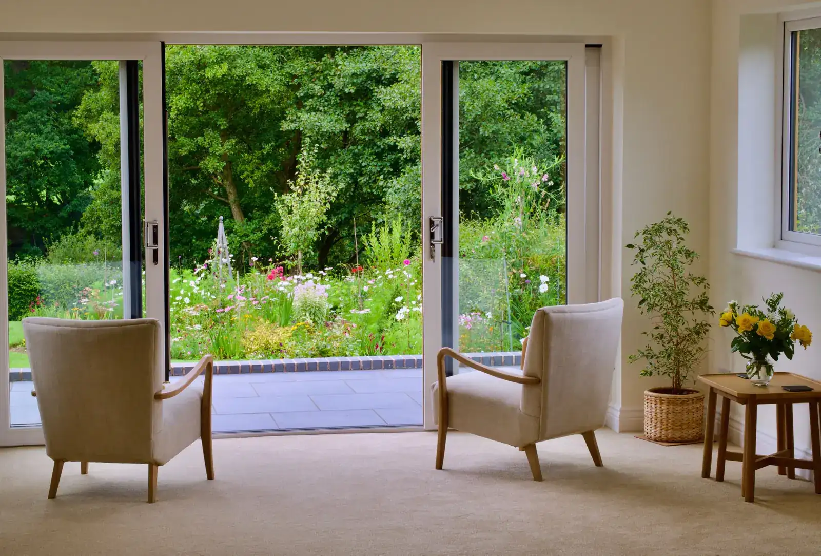 Two armchairs in a bright room facing open doors onto a garden